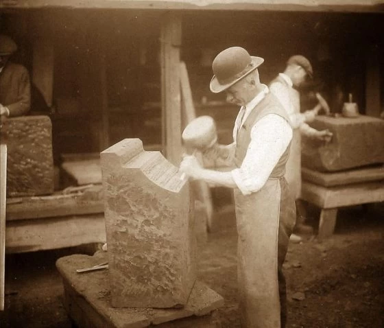 A stone mason dressing a cornice stone.