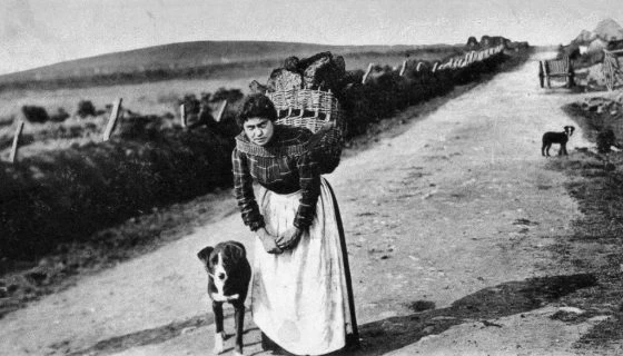 A crofter carring a basket of peat for fuel.