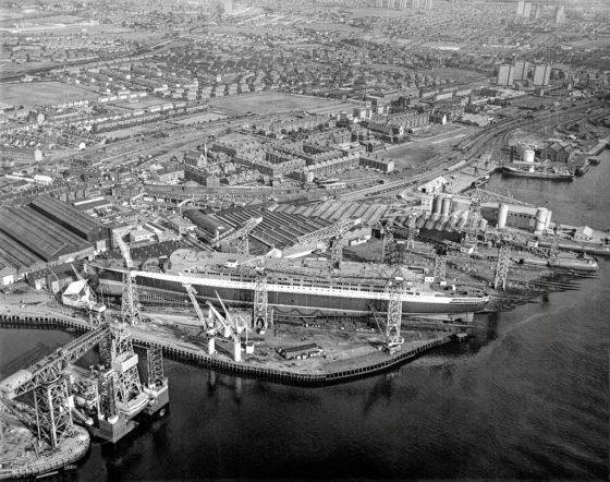 Aerial view of the Cunard liner RMS Queen Elizabeth 2 under construction at the shipyard of John Brown and Company, Clydebank. 
Image courtesy of National Records of Scotland.